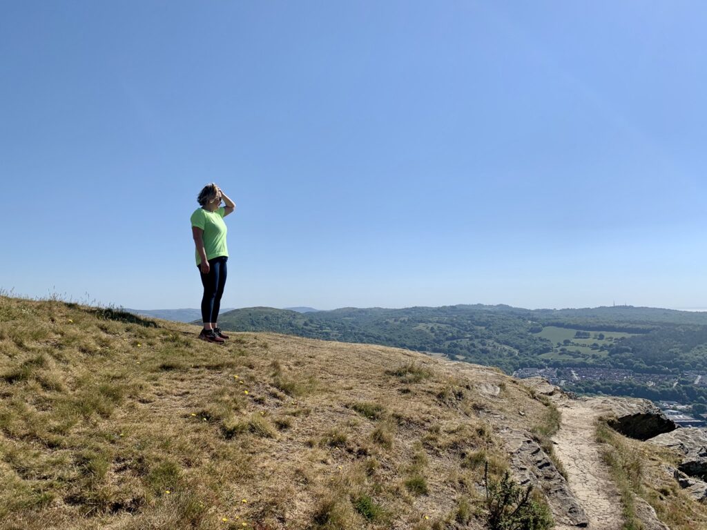 Maren standing on top of the Garth Hill in South Wales near Cardiff, looking out over  summer landscape. 